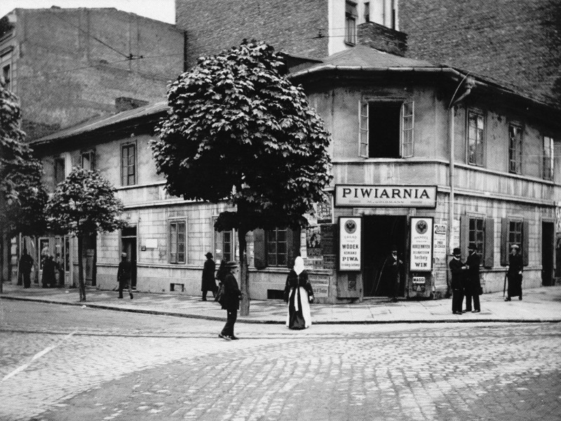 Archiwalne zdjęcie baru w Krakowie – niewielki narożny budynek z szyldem „Piwiarnia” i przechodniami przed wejściem.