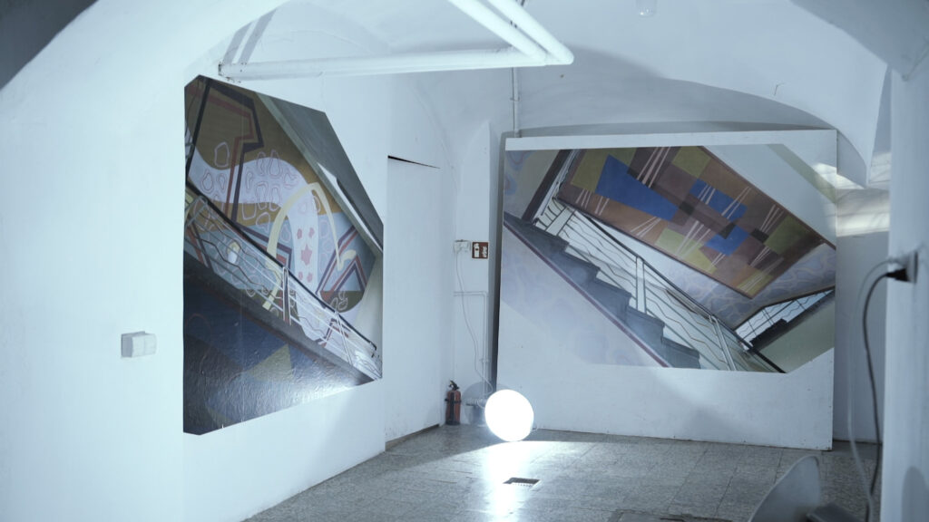 Wystawa z wielkoformatowymi fotografiami Bartosza Koczenasz dokumentującymi murale Stanisława Jakubczyka na klatce schodowej.