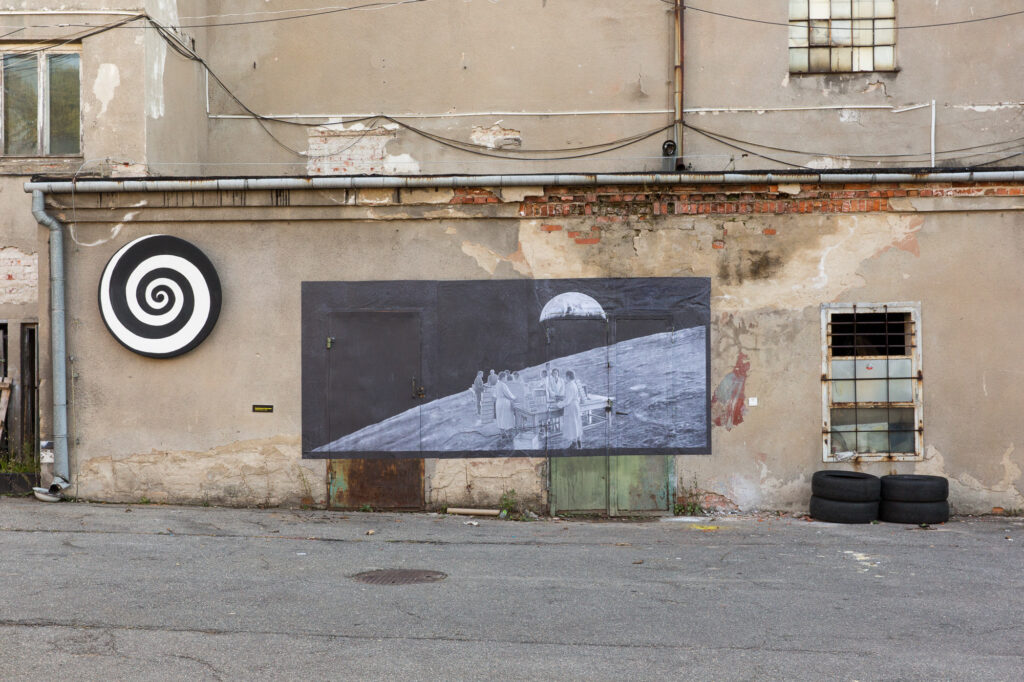 Spirala namalowana na antenie satelitarnej i kolaż na bazie archiwalnego zdjęcia z pracownikami fabryki zainstalowany na elewacji zabytkowej Drożdżowni w Krakowie.