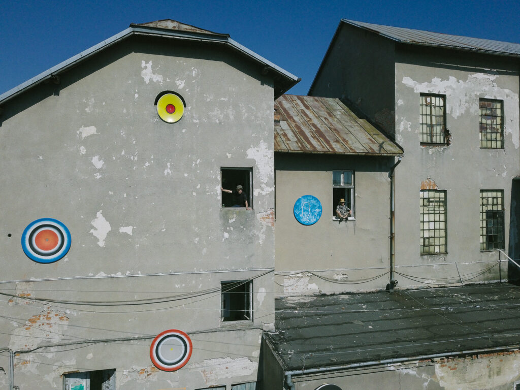 Postindustrialna fasada Drożdżowni z zamontowanymi okrągłymi elementami instalacji site-specific.