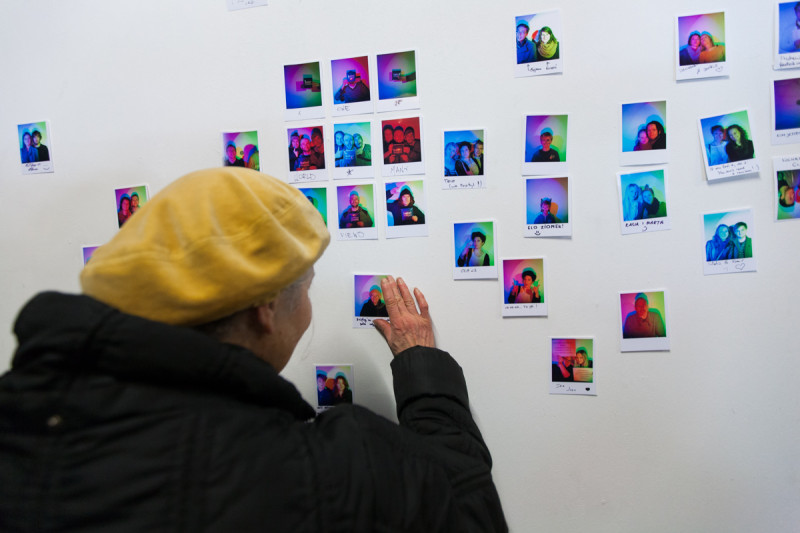 Visitor examining instant RGB self-portraits displayed on gallery wall, interactive installation view.