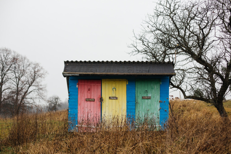 Niebiesko-kolorowy wychodek, site-specific „Teleporter” z kolorowymi drzwiami.