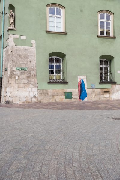 Poza przeszłością i teraźniejszością, kolaż fotograficzny na elewacji kamienicy na Małym Rynku w Krakowie