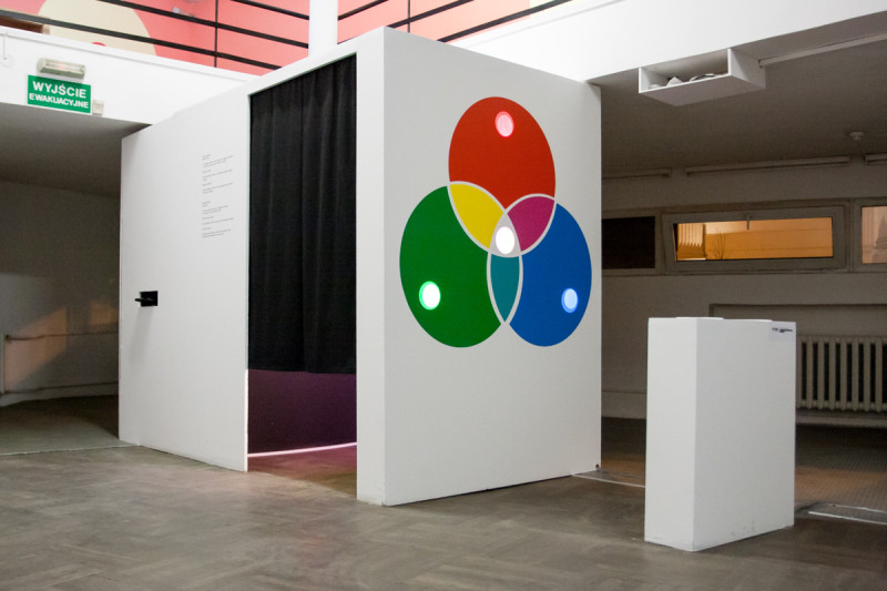 Interactive photo booth installation with RGB color diagram on white cubic structure, exhibition view at Bunkier Sztuki.