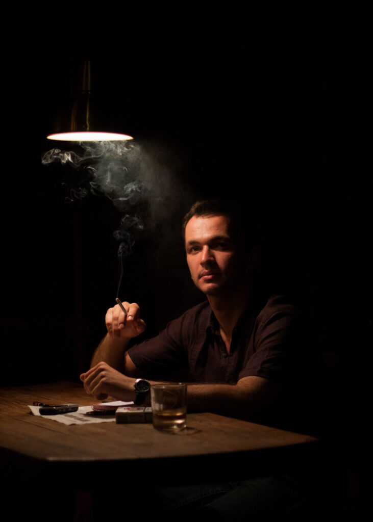 Portrait from the “21 Jewish Krakowians” series documenting contemporary Jewish life in Krakow. Journalist Mateusz Żurawik smoking a cigarette in the bar.