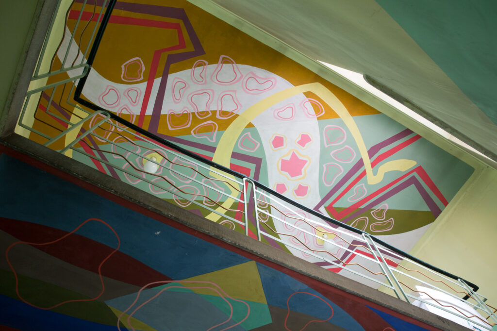 Abstrakcyjny mural geometryczny zintegrowany z architekturą klatki schodowej.