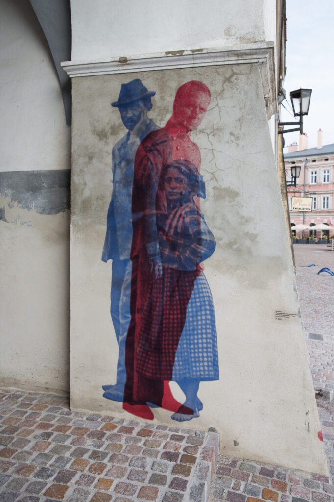 Nakładające się sylwetki mieszkańców z pocztówek z początku XX wieku, instalacja w Jarosławiu.