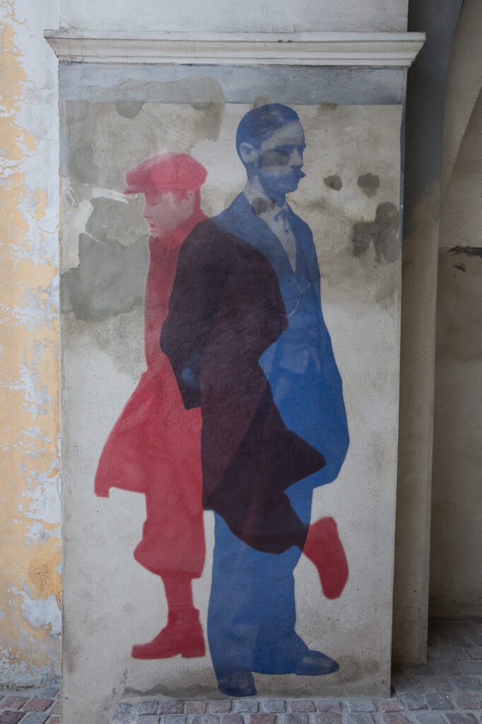 Zestawienie historycznych i filmowych postaci w kolażu na filarze arkad w Jarosławiu.