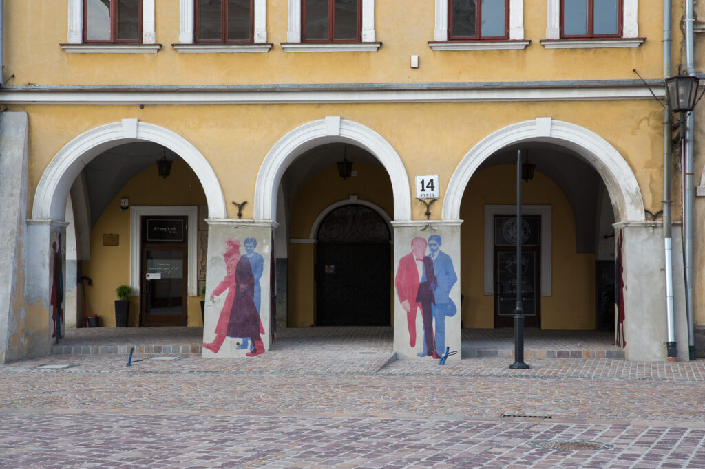 Sylwetki mieszkańców i bohaterów filmowych w kolażach na filarach arkad Rynku w Jarosławiu.